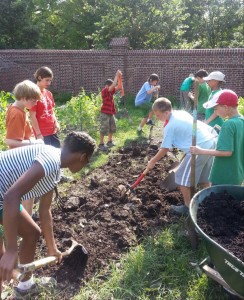 Campers and counselors at Camp Kumquat prepare a garden bed for planting. 