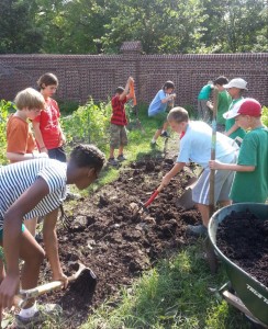 Campers and counselors at Camp Kumquat prepare a garden bed for planting.
