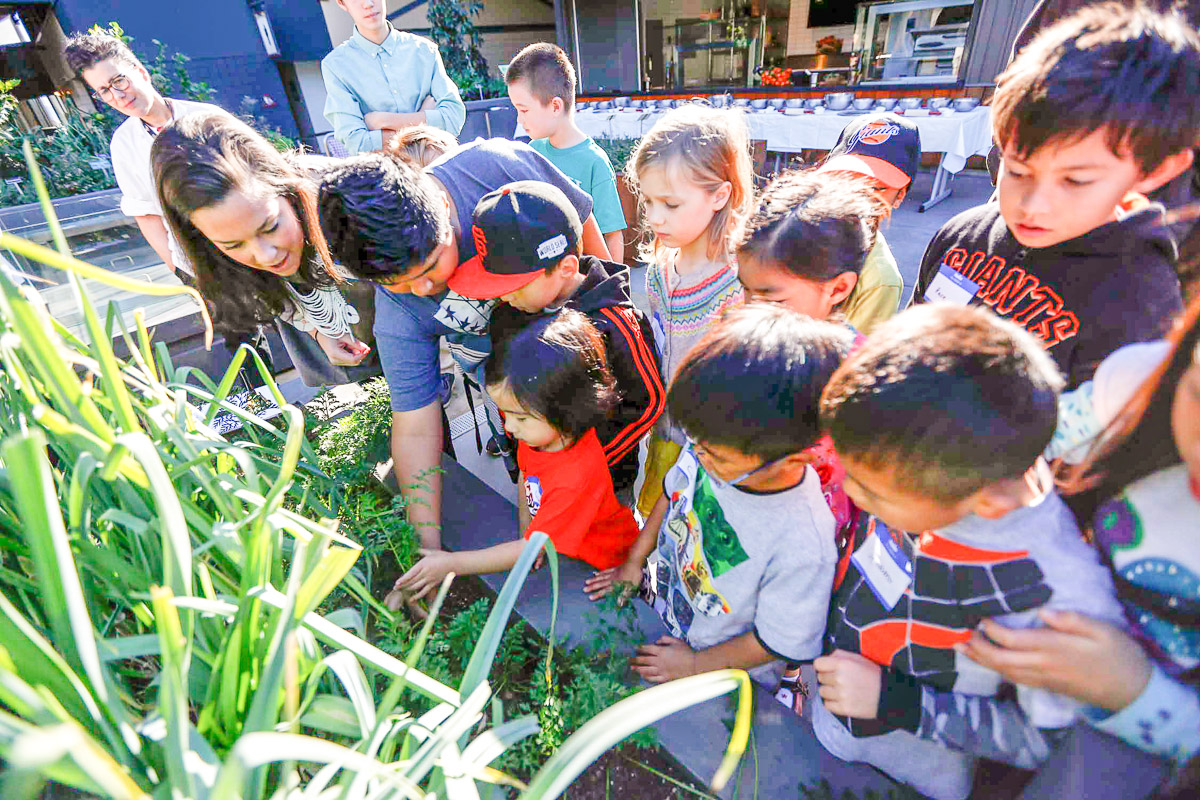 Bon Appétit Community Development Manager Hannah Schmunk shows a group of visiting kids how carrots grow