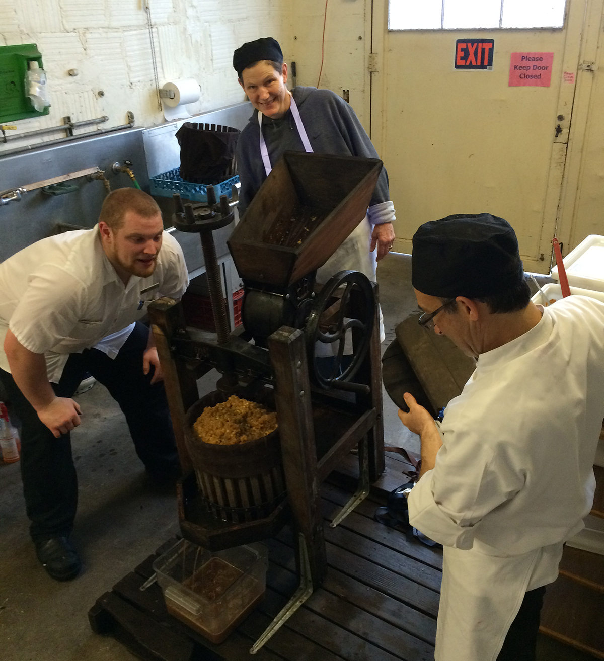 Storeroom Manager Mike Wilson, FOH Server Lynne Rice, and Chef/Manager Paul Lieggi pressing apples