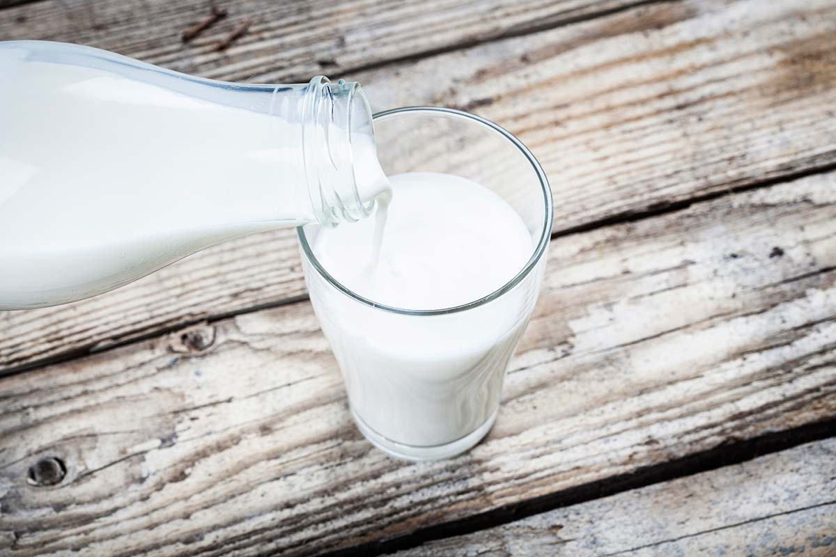 Pouring-a-glass-of-milk-wooden-table-000068812089_1200px