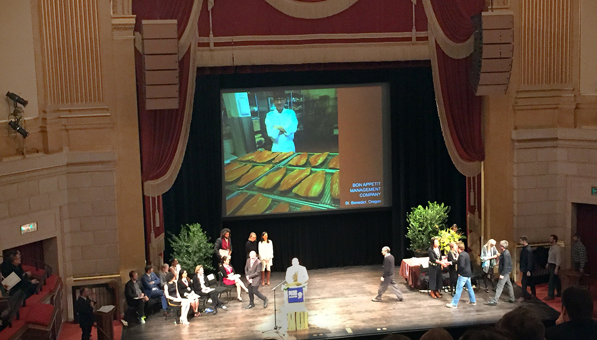 Paul Lieggi walks across the stage after accepting his medal from celebrated restaurateur Alice Waters