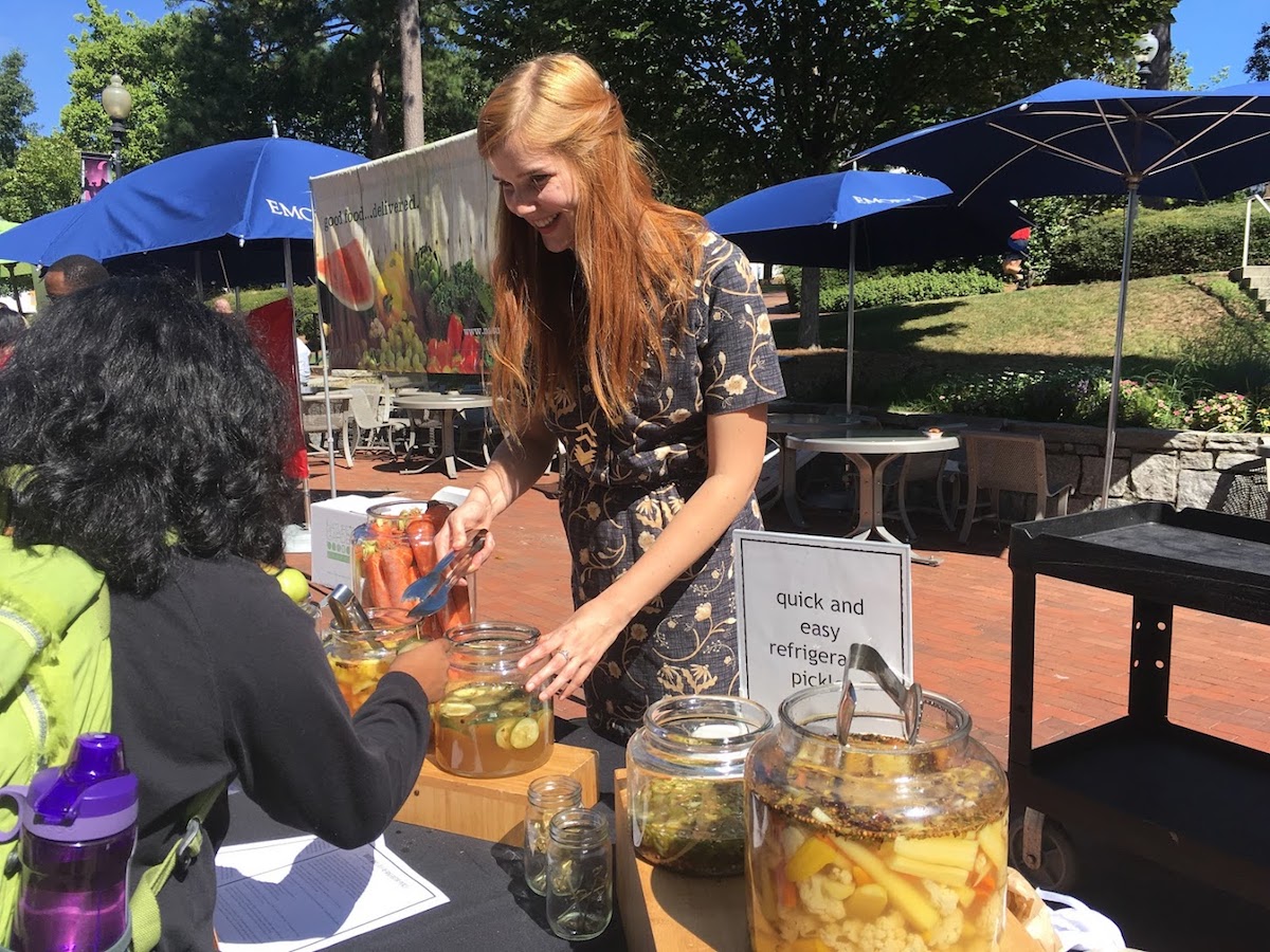 Caroline Ferguson standing behind food food stand, handing out pickles