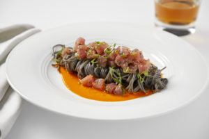 Plate of squid ink spaghetti with tuna and roasted red pepper sauce