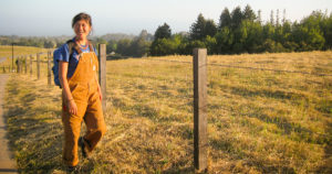 Young woman in field wearing overalls