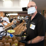 man in face mask holding salad