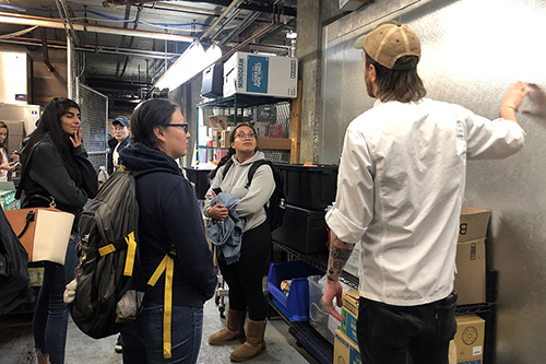 Sous Chef Loren Larsen[ckTKbp] takes University of San Francisco students from a Sustainable Business Strategies class on a kitchen tour