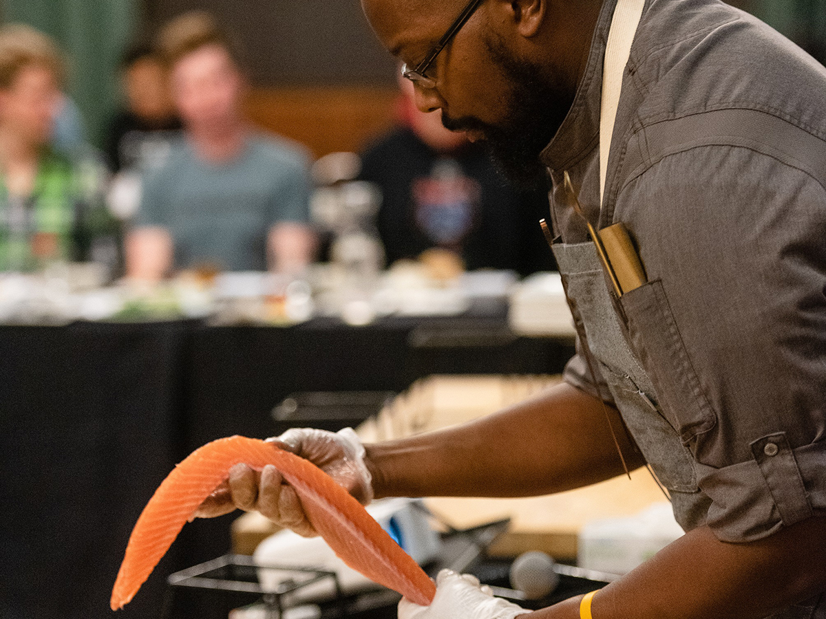 Catering Executive Chef Juwanza Thomas demonstrating how to break down a side of salmon