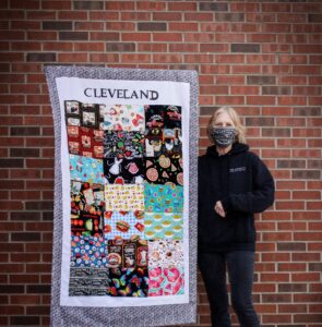 Woman stands next to commemorative quilt