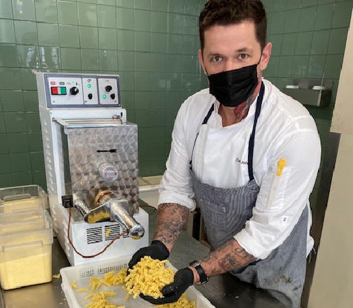 chef standing next to a pasta extruder