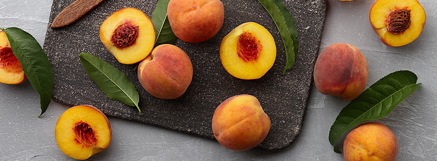 Fresh peaches fruits with leaves on textured stone background, top view