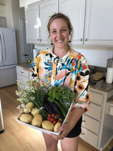 Bon Appétit Waste Programs Manager Claire Cummings Bogle holding a box of fresh vegetables.