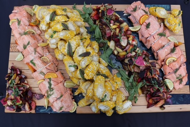 Smoked salmon, corn, and root vegetables spread artfully on a board