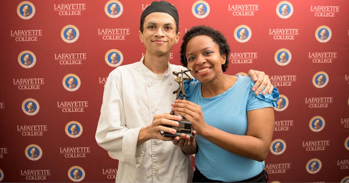 Two smiling people holding a trophy