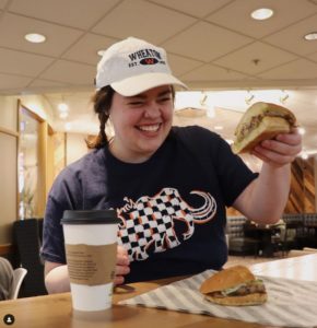 A Wheaton College student poses with a sandwich 