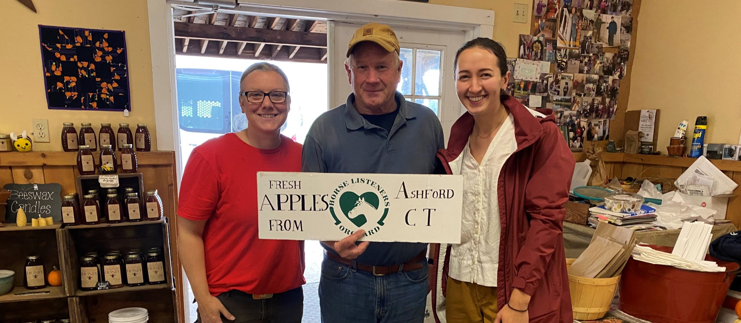 Horse Listeners Orchard Worker Crystal Morawitz, General Manager Rick Hutton, and East Coast Fellow Elise Dudley pose in the orchard’s farm store.