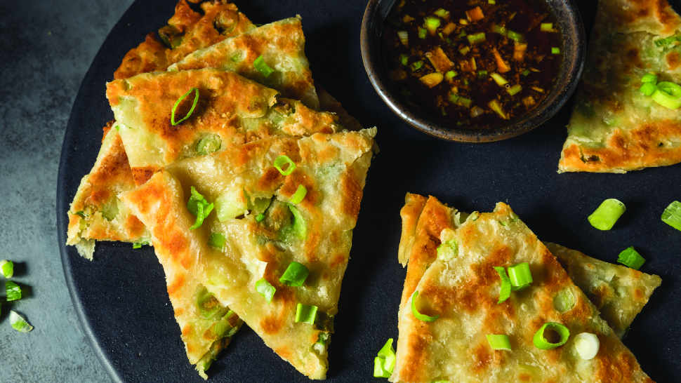 Scallion pancakes topped with scallions atop a black backdrop