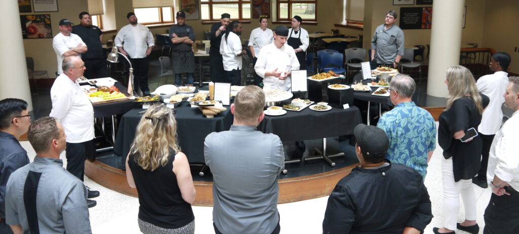 Attendees of a recent Midwest plant forward training at Macalester College look on as Bon Appétit at Macalester Executive Chef Chad Plotnik describes his team's creations