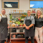 From left: Wellness Team Executive Chefs Shaun Holtgreve and Chris Lenza, and Director of Nutrition and Wellness Terri Brownlee pose with a plant-forward cornucopia at the Macalester College training