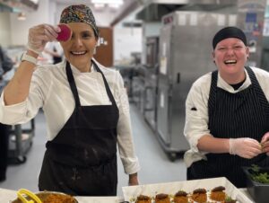 Bon Appétit at Aurora Innovation Executive Chef Amira Cooke (left) holds up a slice of watermelon radish that will go on to garnish the plant-based chorizo medallions created with Bon Appétit at Denison Chef Manager Tiffany Knight (right)