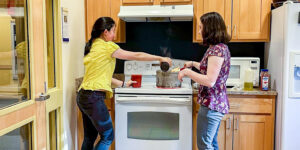 A member of Environmental Carls Organized (ECO) cooks with Fellow Elise Kulers (right)