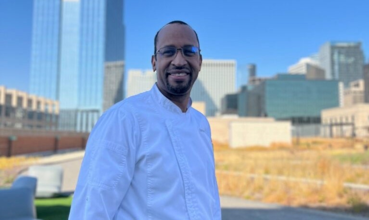 Chef Doran poses on a rooftop with the Chicago skyline behind him