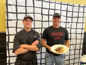 A chef and a farmer stand with a plate of food for the Eat Local Challenge.