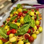 Close-up shot of a salad with figs, tomatoes, and herbs.