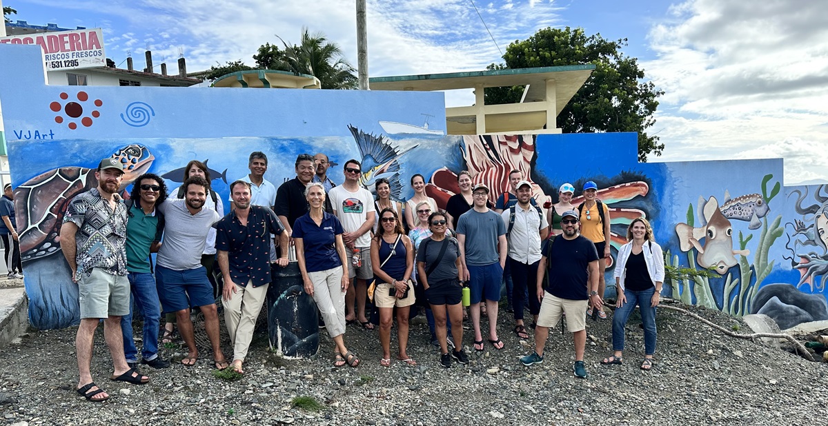 A group of people post in front of a mural.