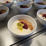 a selection of bowls of dessert with flowers and berries on top.