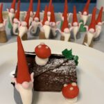 A chocolate dessert on a plate with red and white decorations.