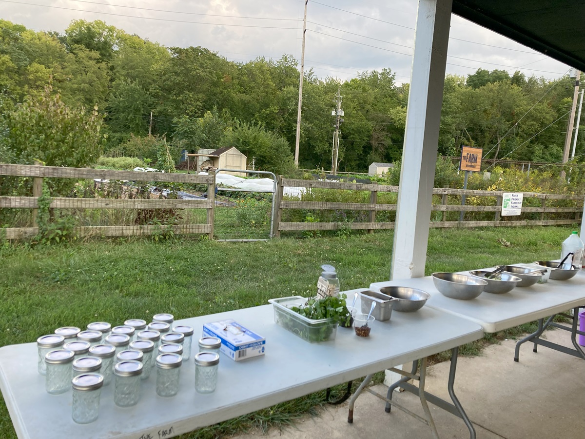 Tables set up outdoors with jars and bowls with a farm in the background. 