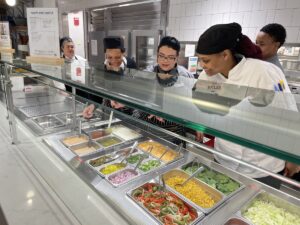 A group of three kitchen workers examine a station in their kitchen 