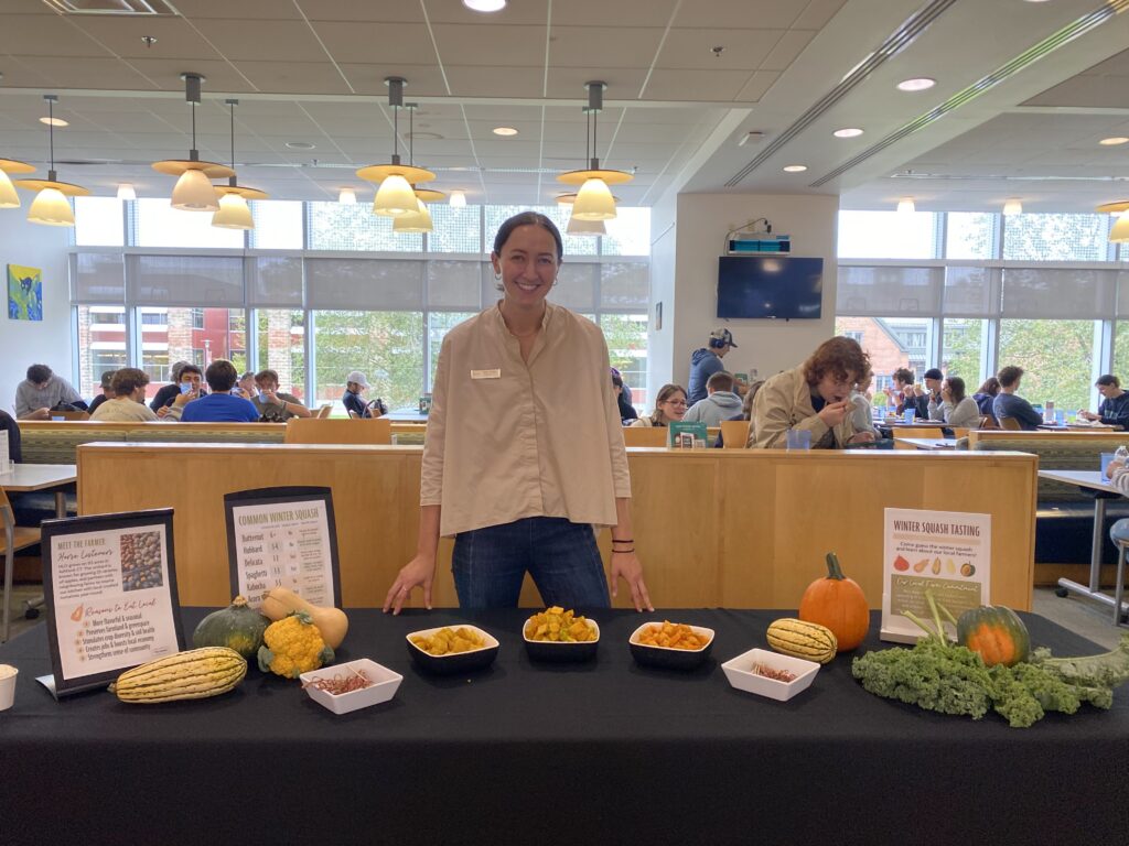 a wpman stands behind table with a display on it of cooked and whole squash