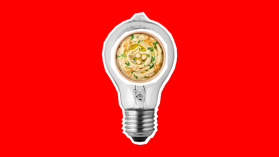 A bowl of hummus inside a light bulb on a red background. 