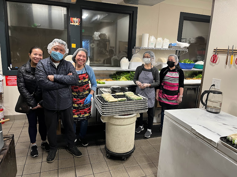 A group of people wearing masks and smiling in a food manufacturing setting. 