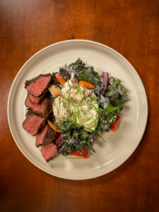 An overhead shot of a plate of medium-rare steak and kale salad. 