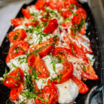 A close-up of a tomato, ricotta, and basil salad.