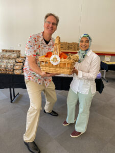 A man and a woman hold a basket of mushrooms together, in front of a mushroom display.