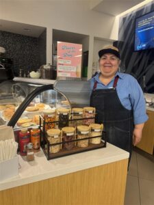 A cafe worker stands alongside her softserve station in a workplace.
