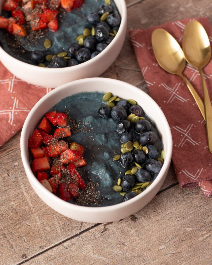 An overhead shot of a breakfast bowl of blue corn "mush" with fresh fruit