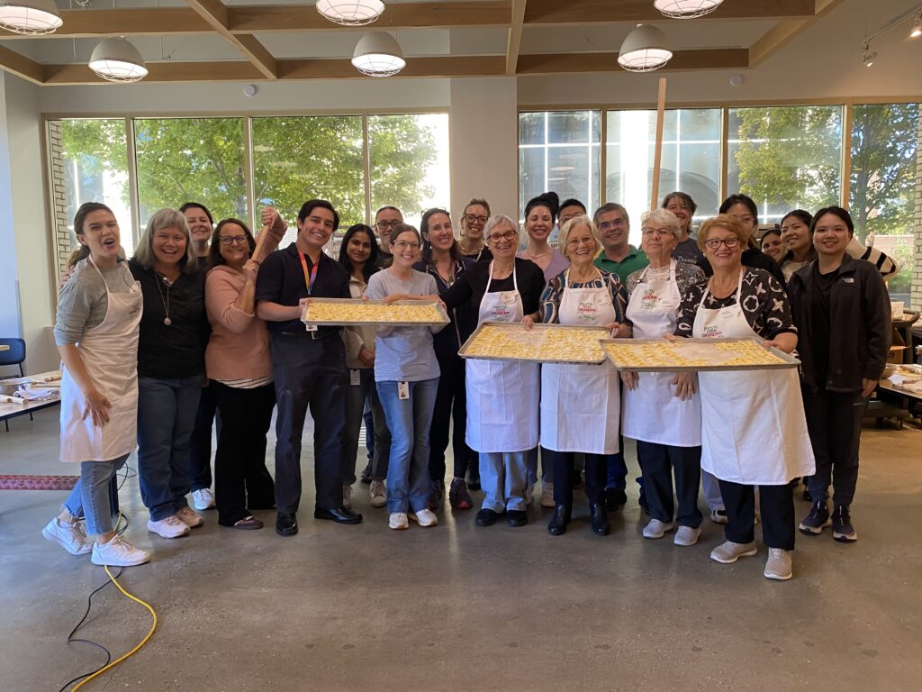 A group of people pose with fresh pasta after learning how to make it in a cooking class. 