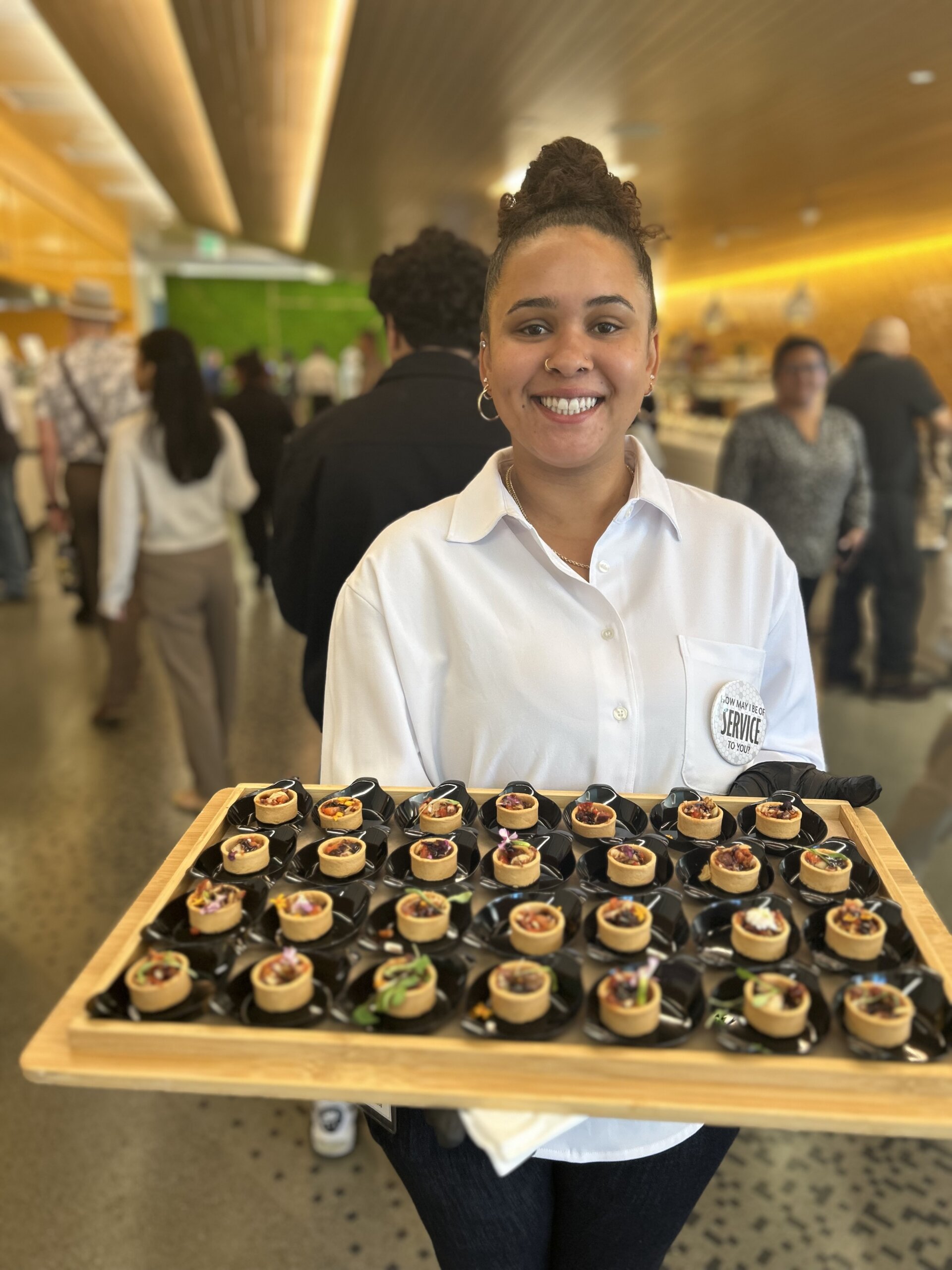 A young woman offers food to guests during a cafe opening.