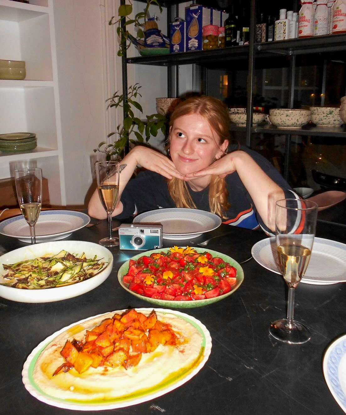 A young woman sits with her head in her hands at a table full of food.
