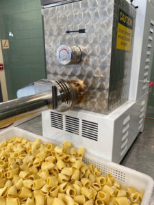 Fresh pasta underneath the pasta extruder