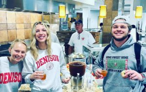 Three diners in front of a vessel full of apple cider in a dining hall for a food service company's Eat Local Challenge. 